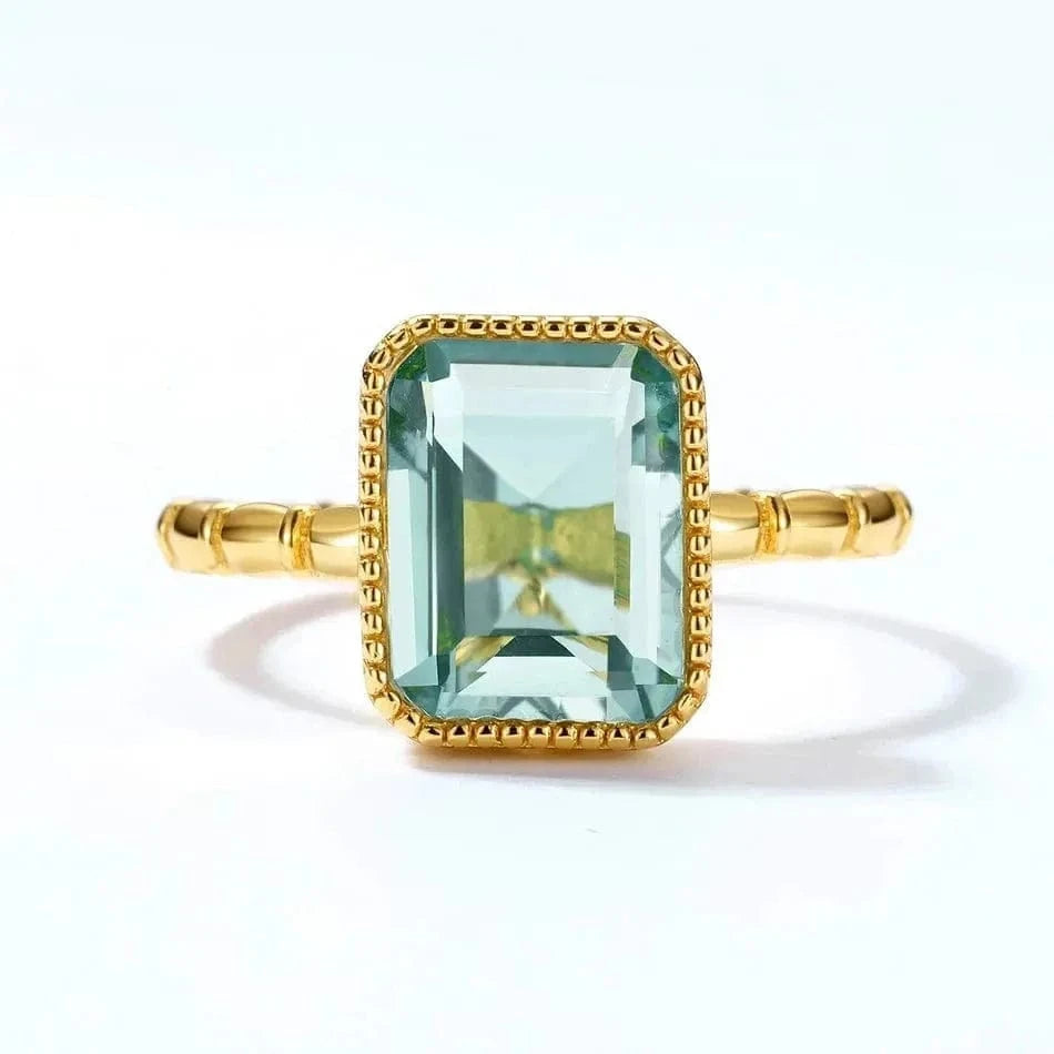Gold ring with a green gemstone on a white background