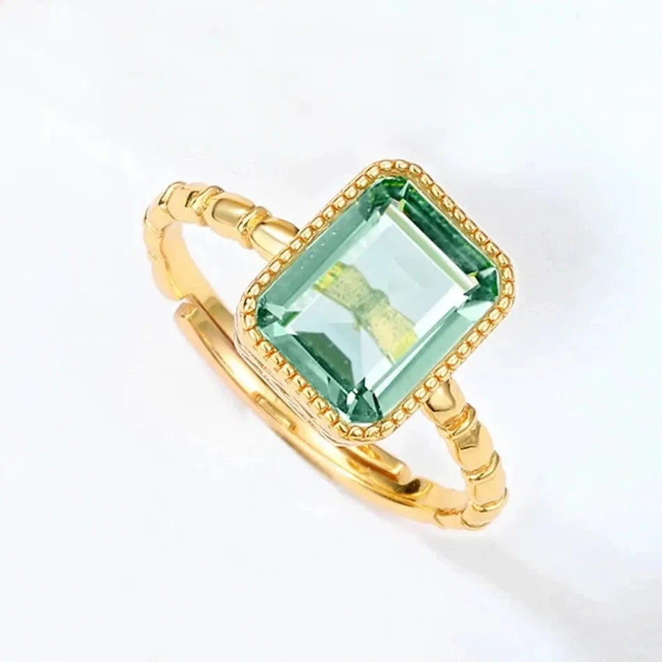 Gold ring with a green gemstone on a white background