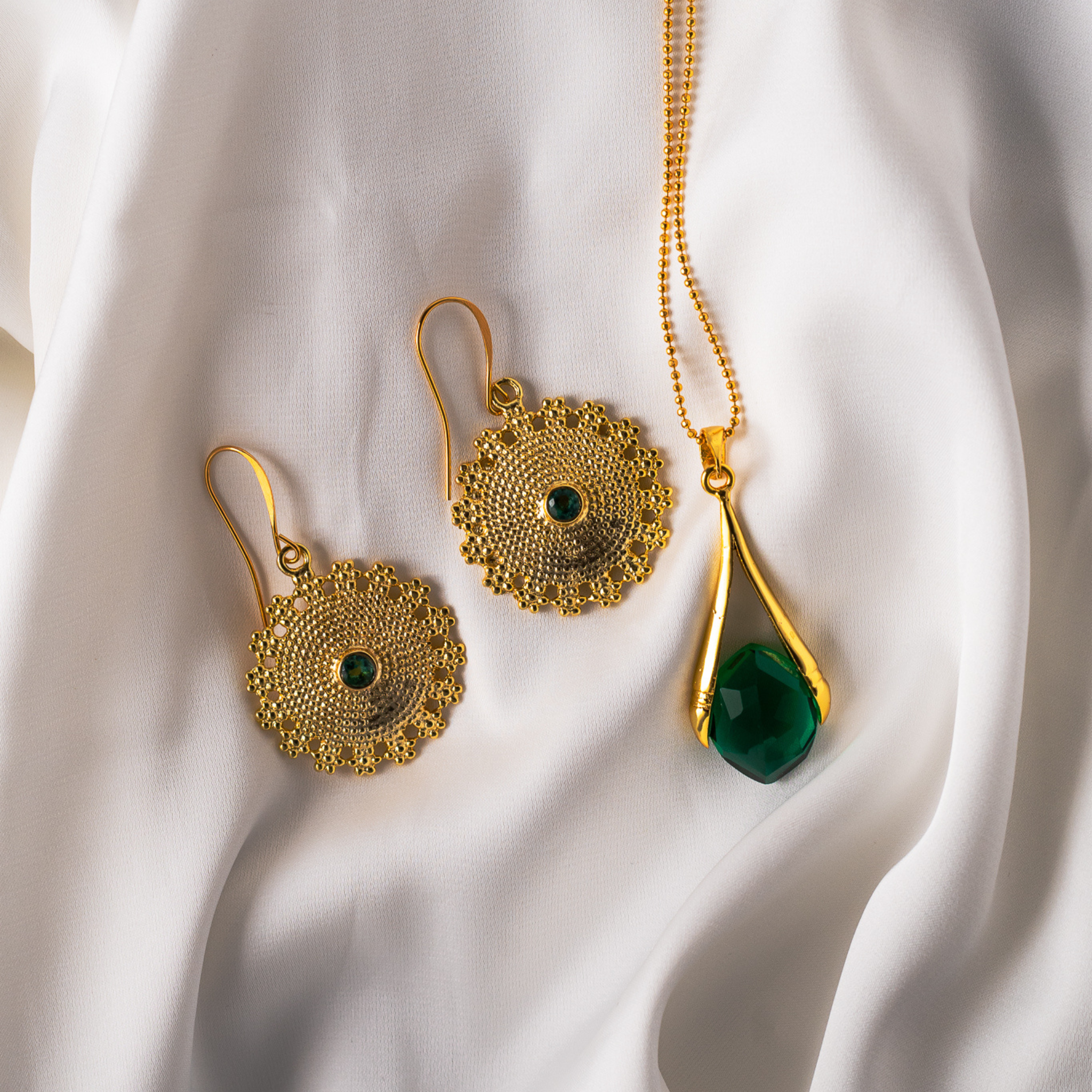 Discover the Emerald Green Medallion Earrings with gold-plated sacred geometry medallions and faceted emerald green quartz stones. Part of the Birthstone Collection.
