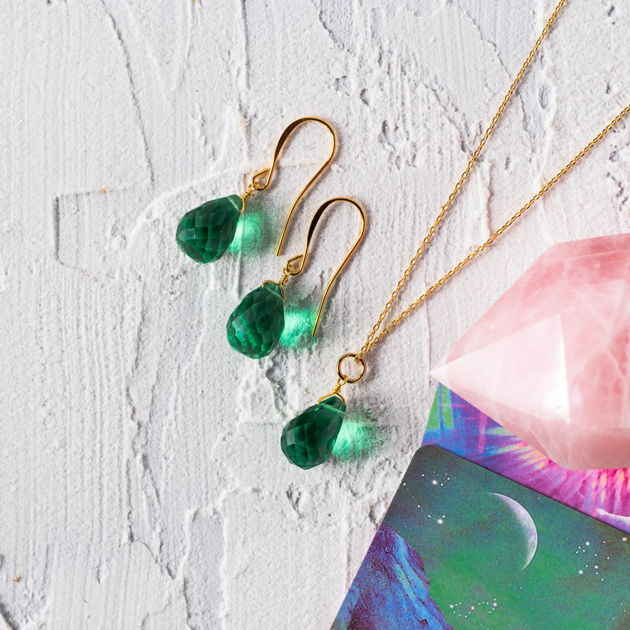 Gold-plated earrings featuring vibrant green faceted pear-shaped glass drops in a delicate wire-wrapped design, symbolizing renewal, abundance, and Heart Chakra energy.