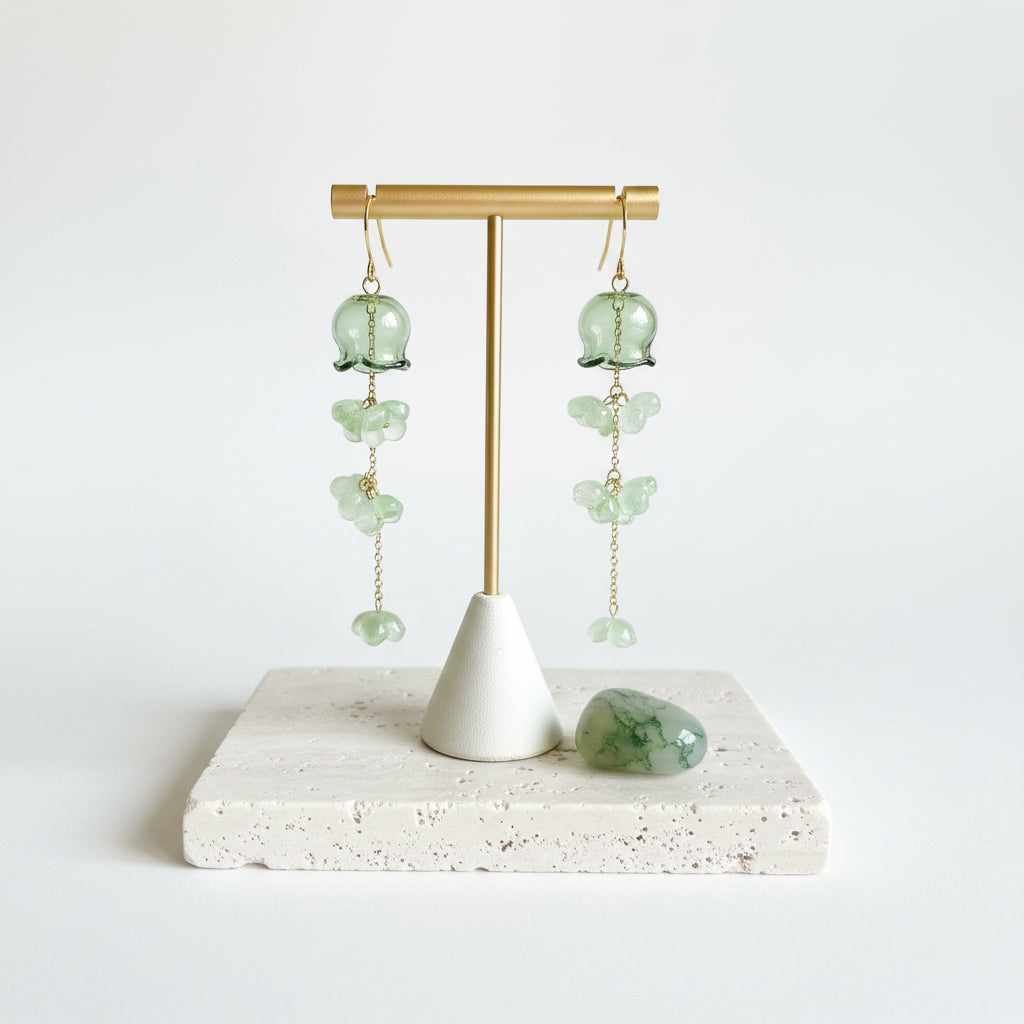 Green glass jellyfish earrings hanging, gold floret drops in motion