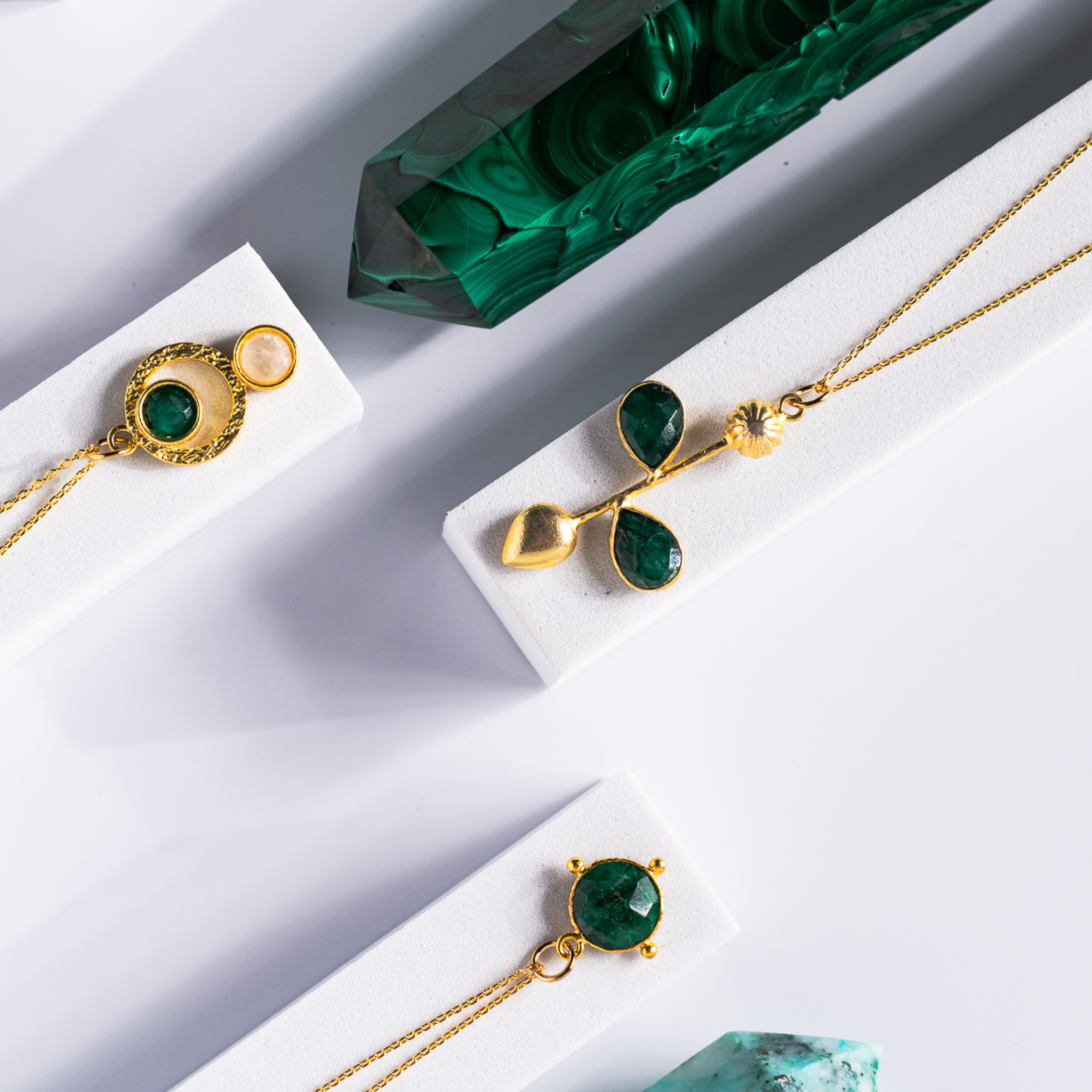 Gold-plated pendant necklace and matching earrings featuring brushed sacred geometry-inspired circle patterns. The pendant and earrings are adorned with vibrant emerald and luminous moonstone stones, symbolizing growth, intuition