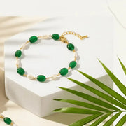 Green beaded bracelet on a white surface with a palm leaf