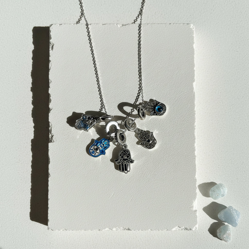 Three sterling silver hamsa hand pendants — blue eye, double layered and cutout — shown together on a chain