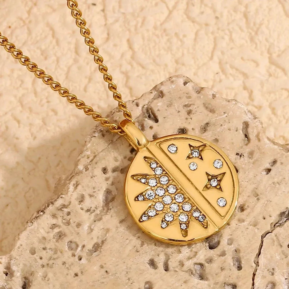 Gold necklace with a leaf design pendant on a textured beige surface