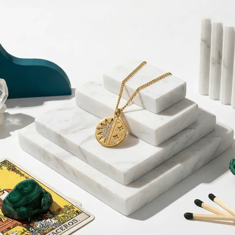 Gold necklace on a marble tiered stand with crystals and tarot card in the background