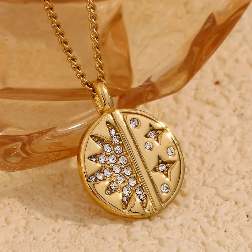 Gold necklace with a decorative pendant on a textured beige surface