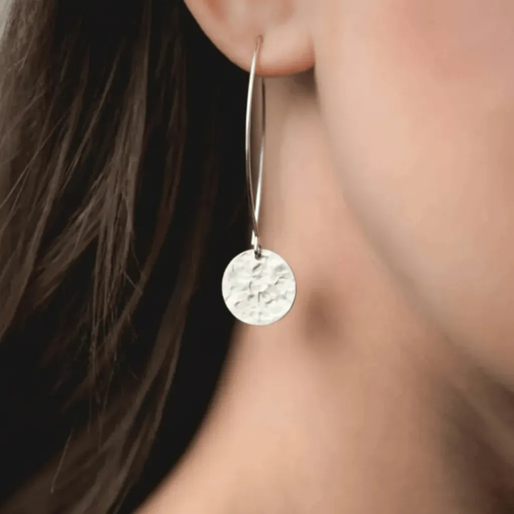 silver earring worn by a person with blurred background