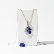 Sterling silver hamsa charm in deep blue enamel, shown against a plain background