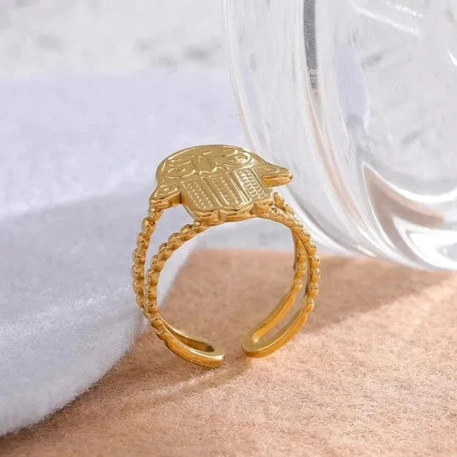 Gold ring with intricate design on a white and beige background