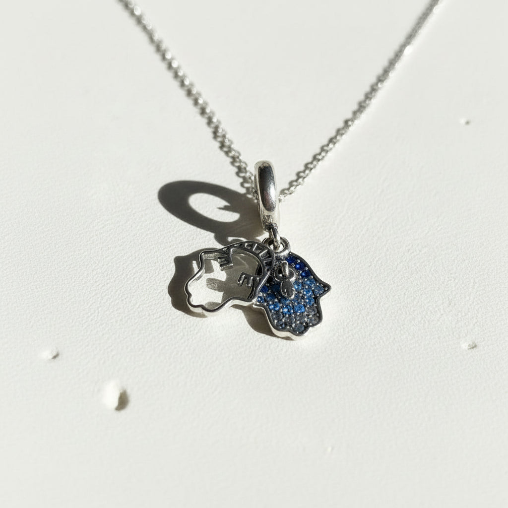 Sterling silver hamsa hand pendant with a raised overlay hand, shown front on