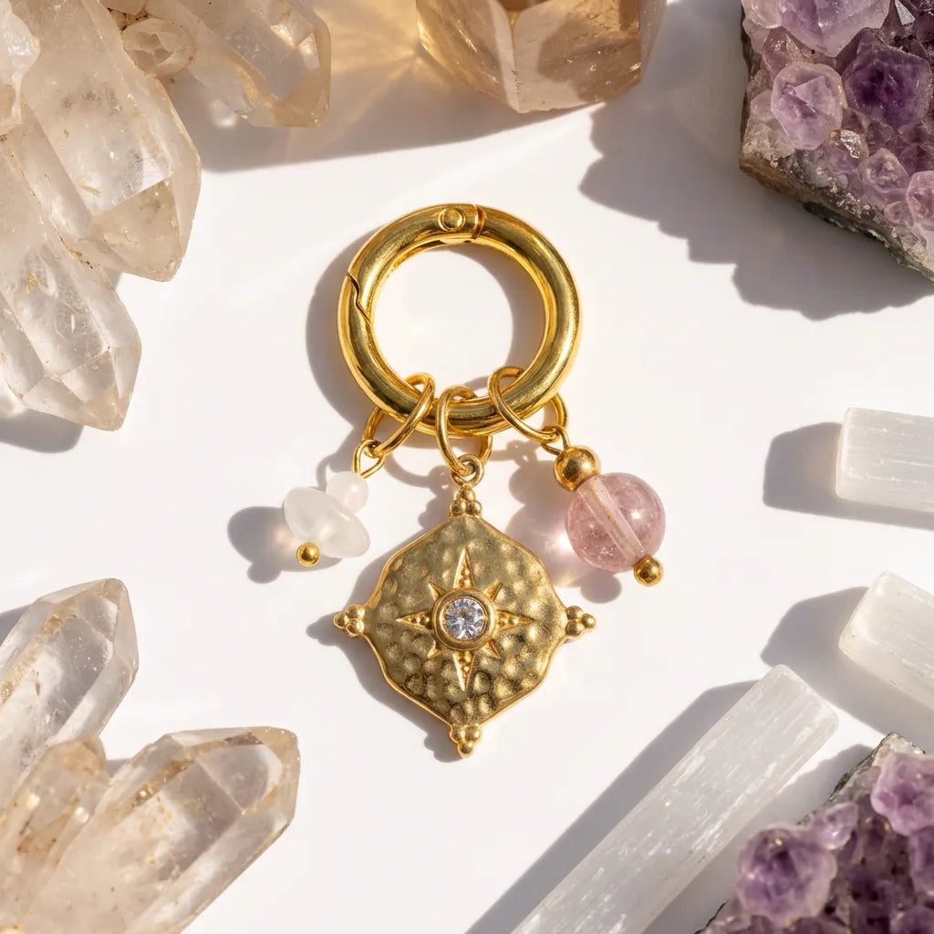 Gold charm with pink beads on a white surface with crystals