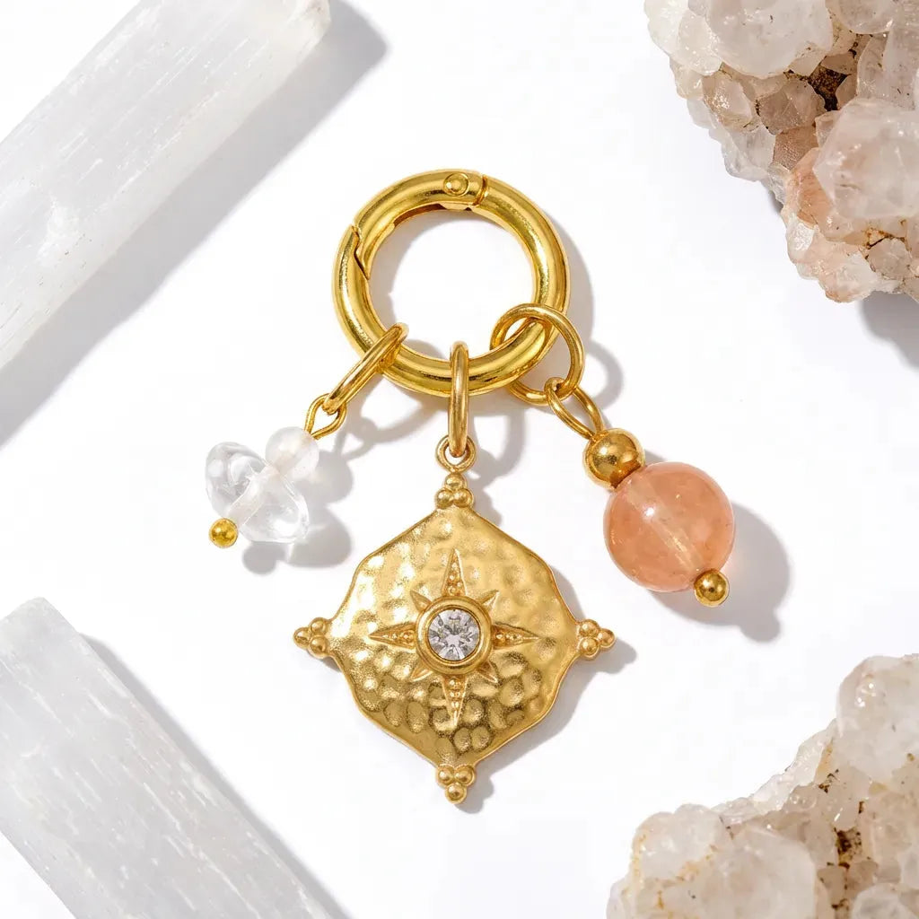 Gold keychain with decorative pendant and beads on a light background