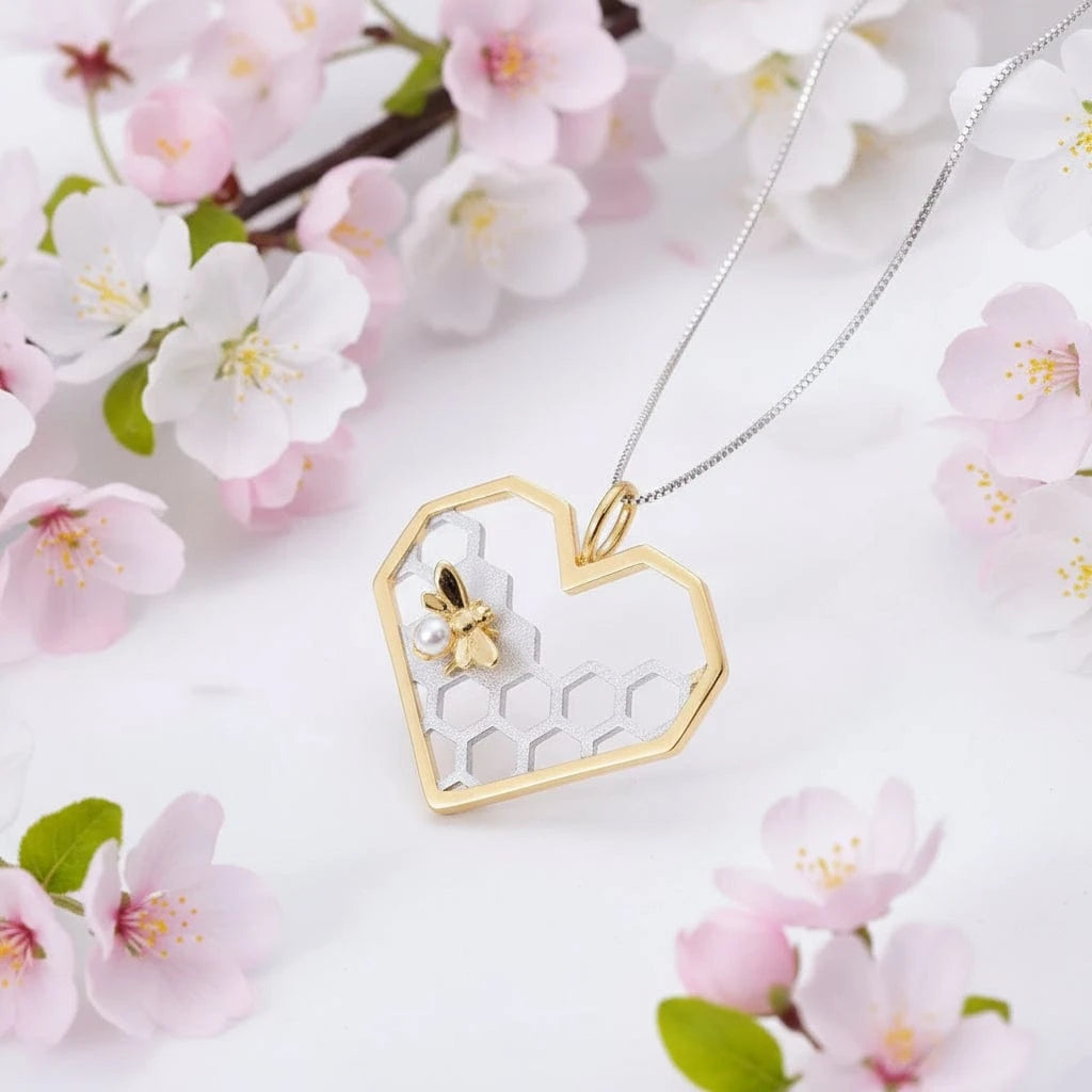 Heart-shaped gold and silver pendant with honeycomb design on a dark stone surface.