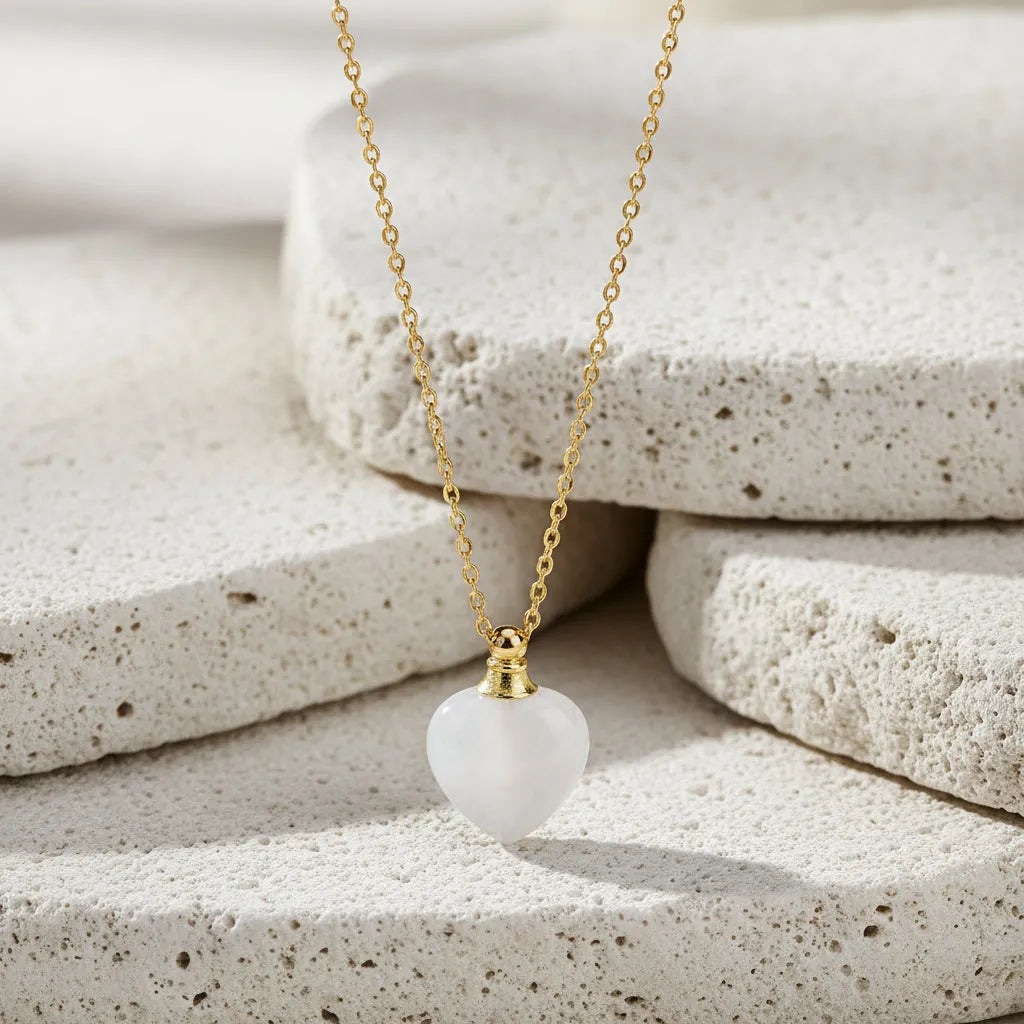 Gold necklace with a heart-shaped white pendant on a black background