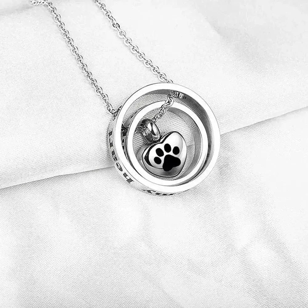 Silver necklace with a heart-shaped pendant featuring a paw print on a white fabric background