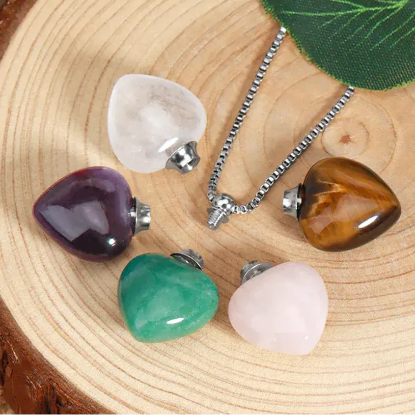 Set of heart-shaped crystal pendants on a wooden surface with a brand logo in the corner.