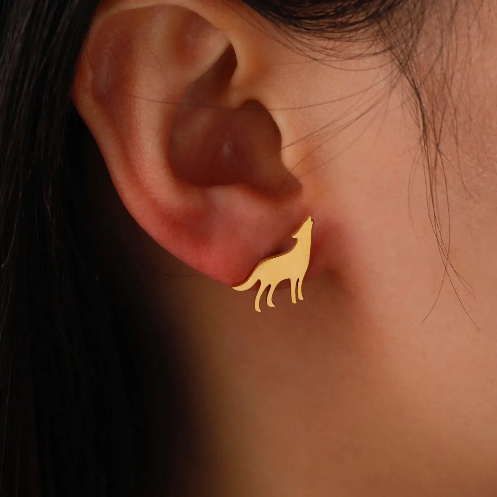 Gold wolf-shaped earring worn on an ear