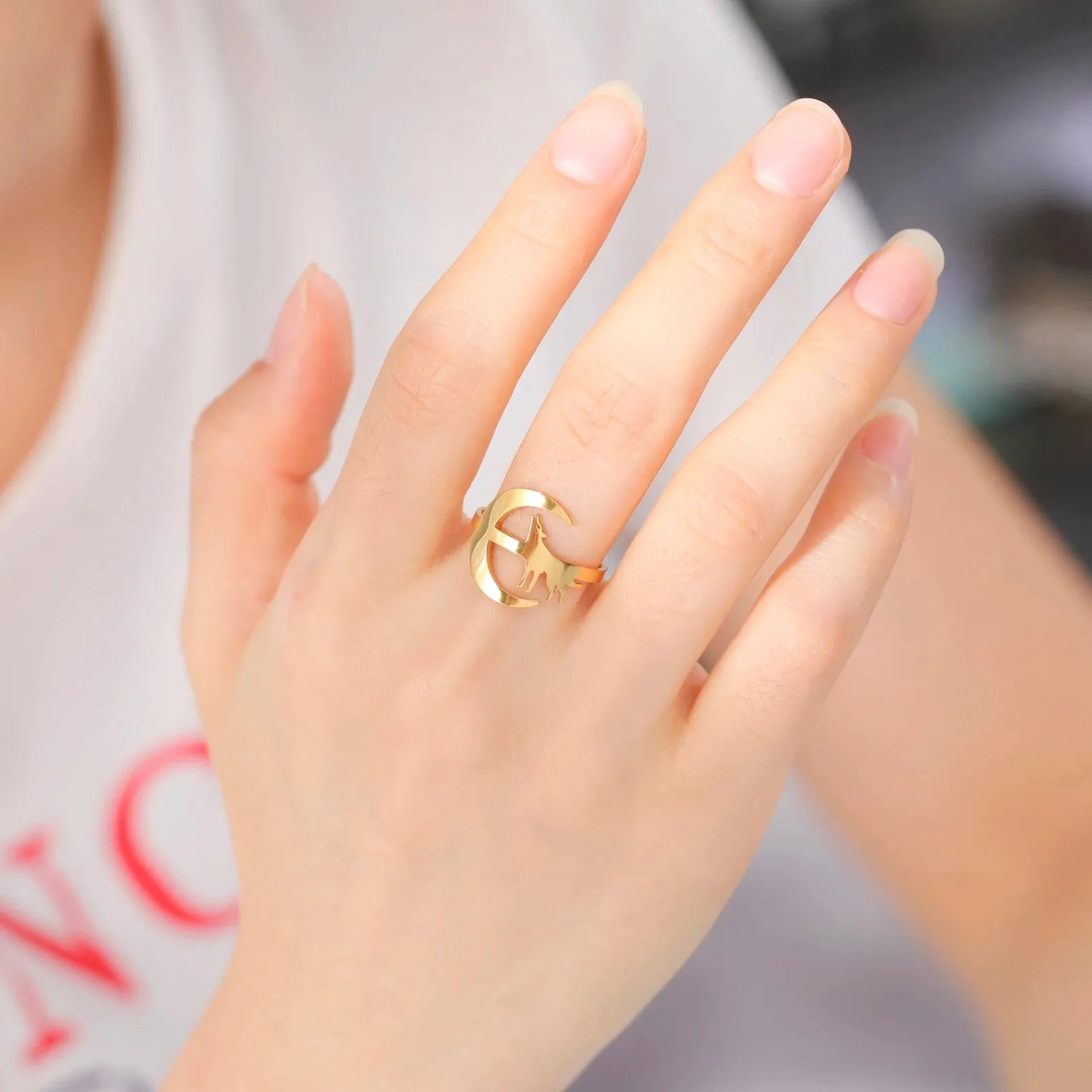 Hand wearing a gold ring with a blurred background