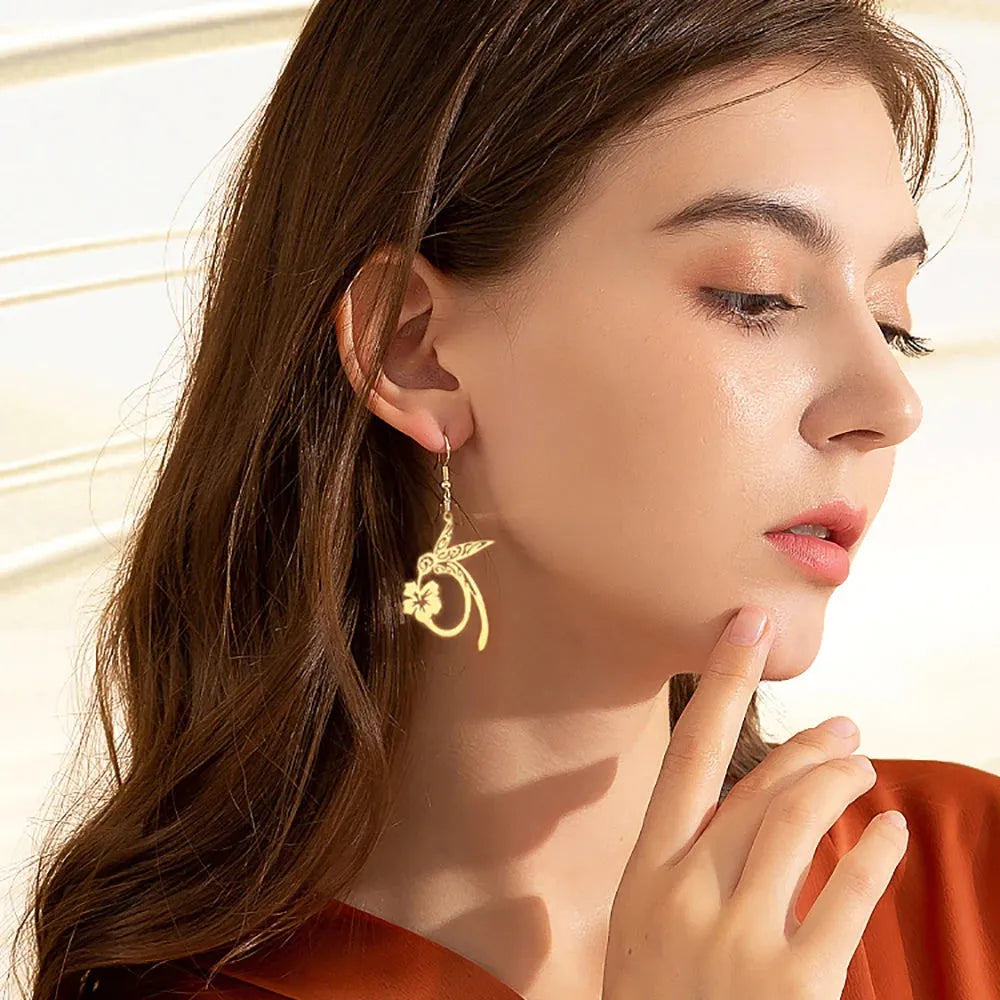 Close-up of a woman wearing gold earrings with a neutral background