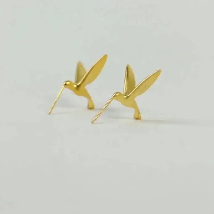 Gold hummingbird-shaped earrings on a light gray background  