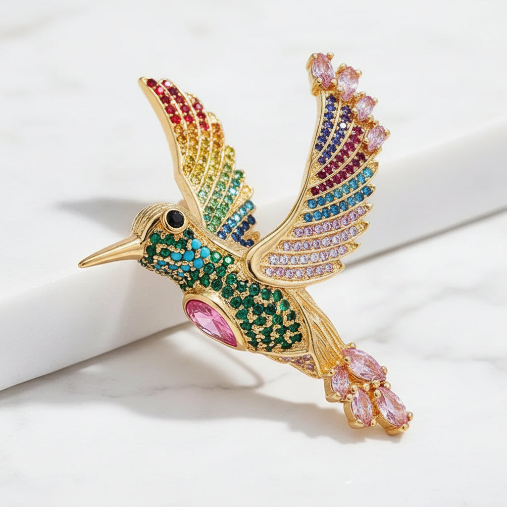 Gold hummingbird brooch with gemstones on a white background 