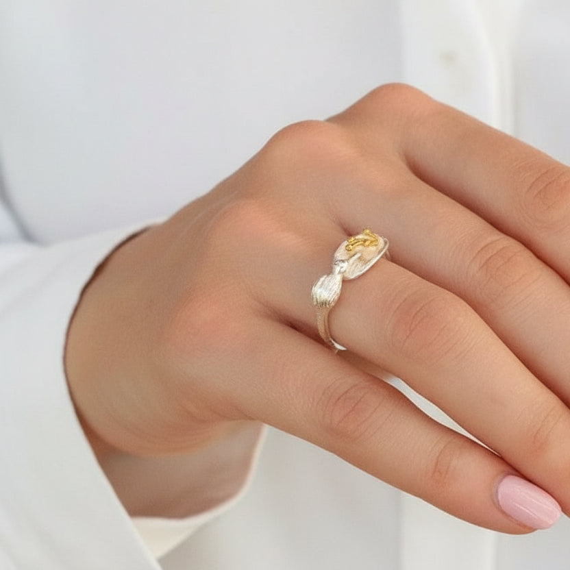 Hand wearing a gold ring with a yellow gemstone against a dark background