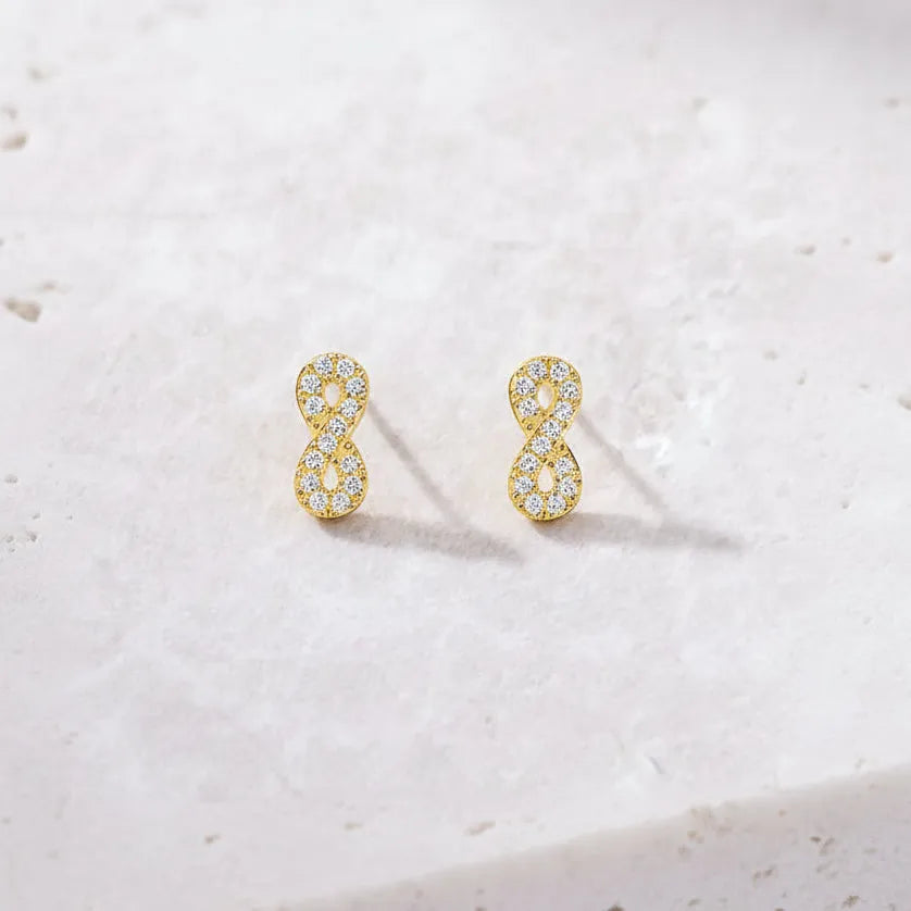 Gold infinity symbol earrings on a light gray background  