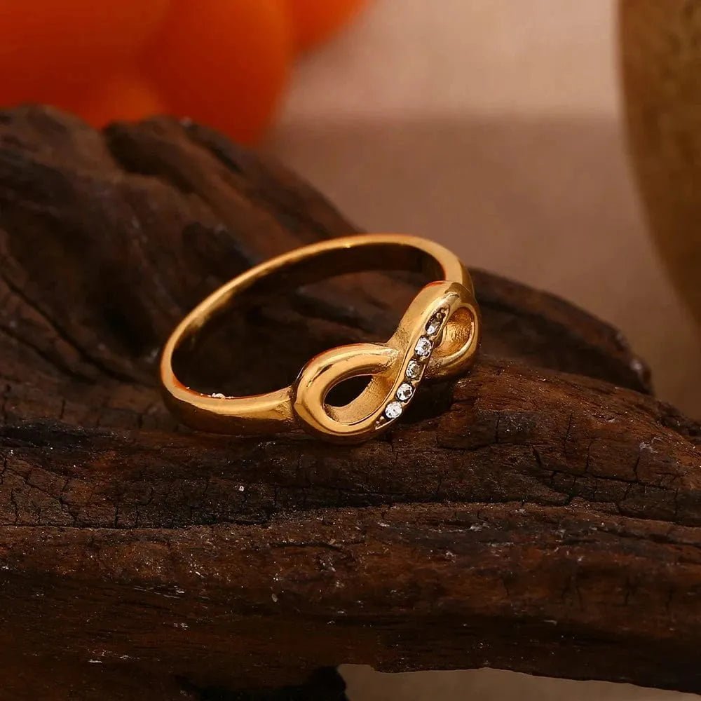 Gold infinity ring with embedded stones on a wooden surface