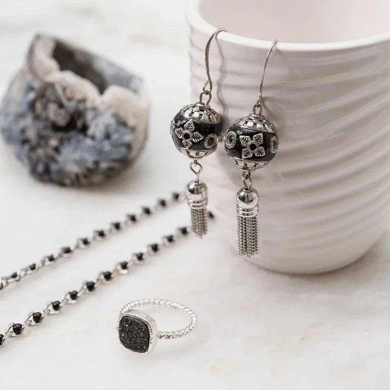 Silver jewelry set with earrings, necklace, and ring on a marble surface.