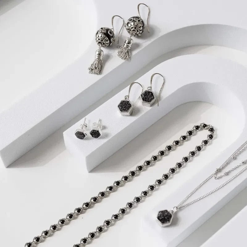 Silver jewelry set with black stones on a white surface