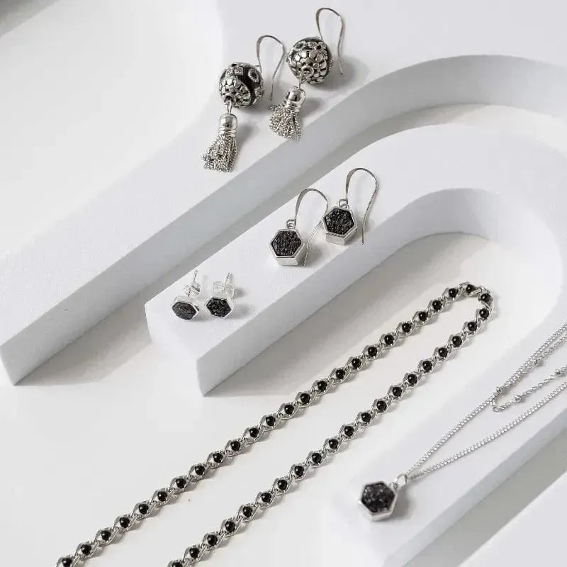 Silver jewelry set with black stones on a white surface