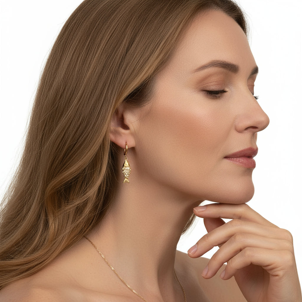 Close-up of a woman wearing gold earrings and a necklace against a neutral background