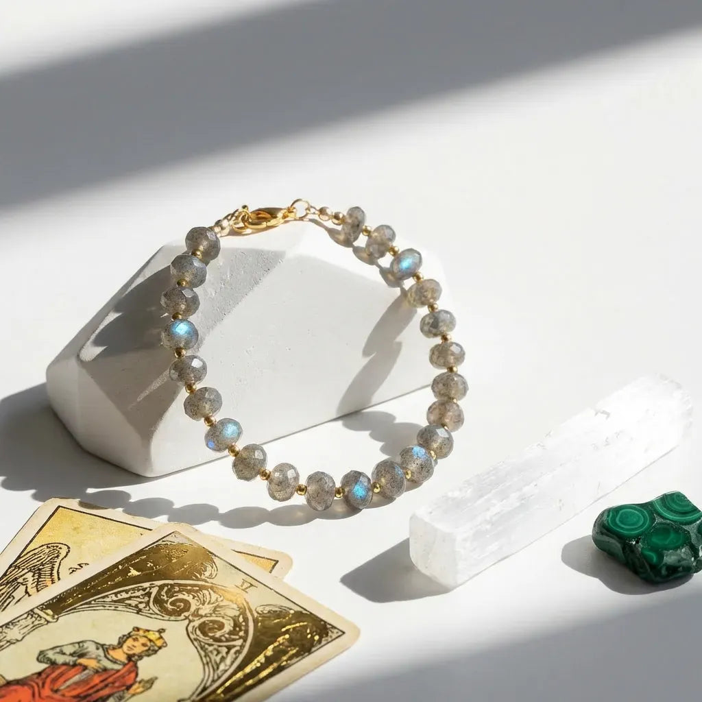 Bracelet with stones on a white surface with tarot cards and a green stone.