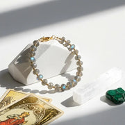 Bracelet with stones on a white surface with tarot cards and a green stone.