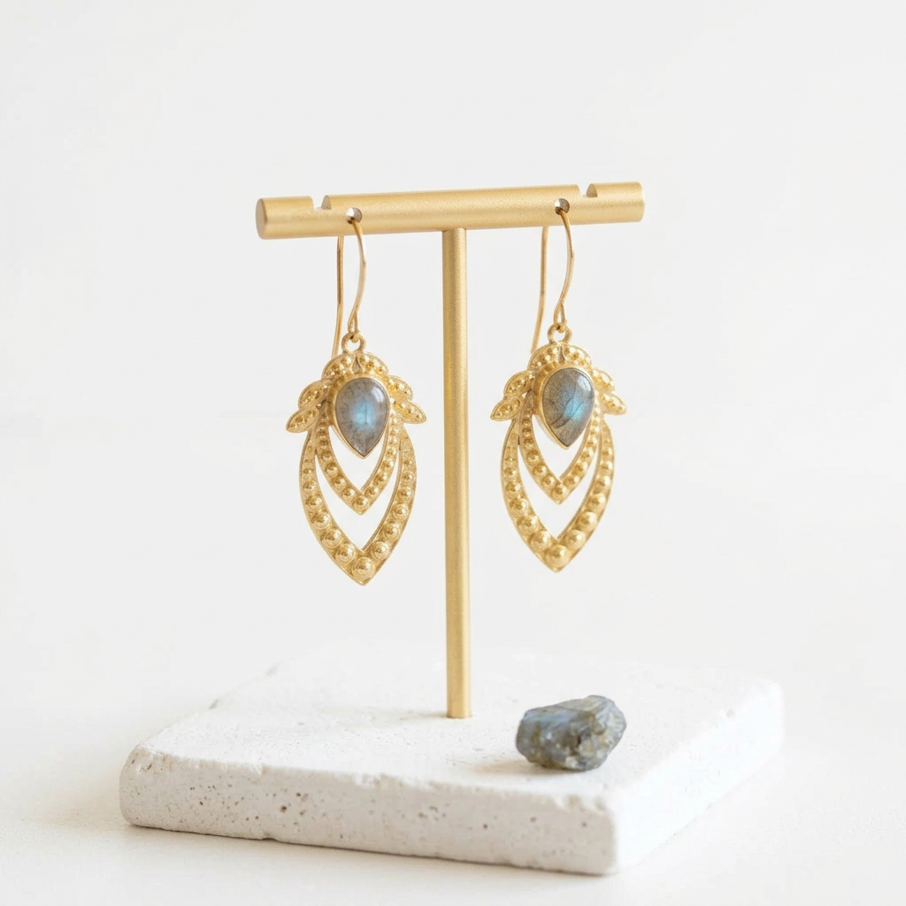 Gold ornate leaf earrings with genuine labradorite, hanging on a gold stand