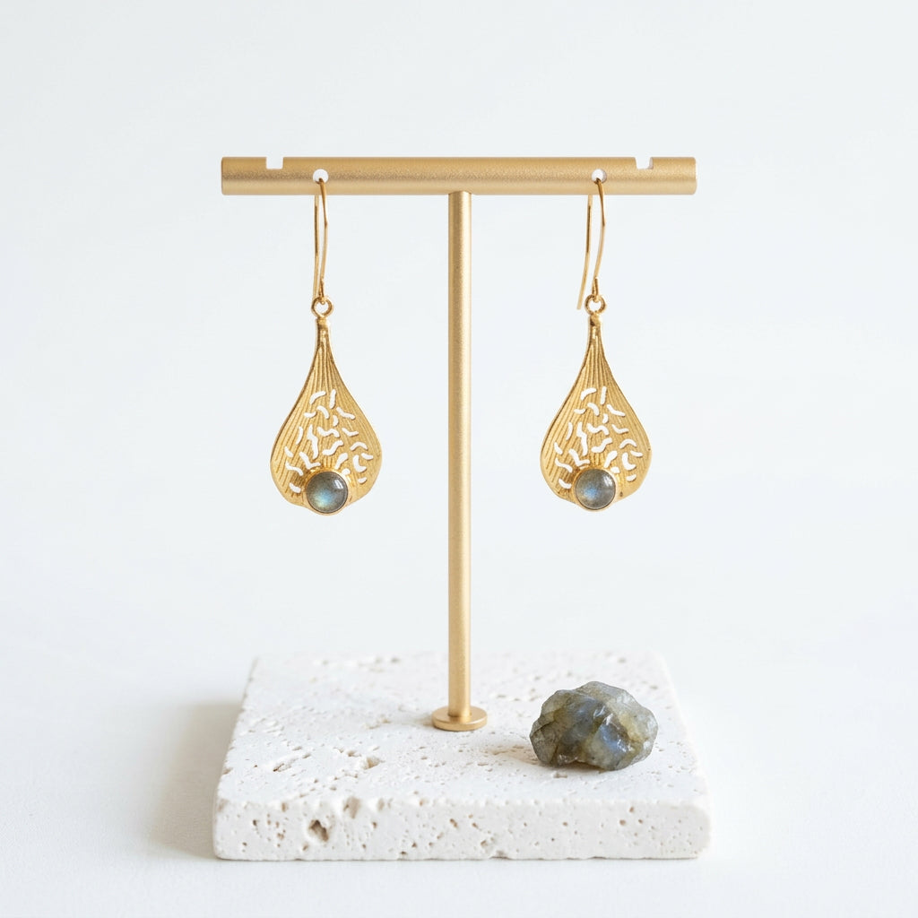 Gold filigree teardrop labradorite earrings hanging on a gold stand