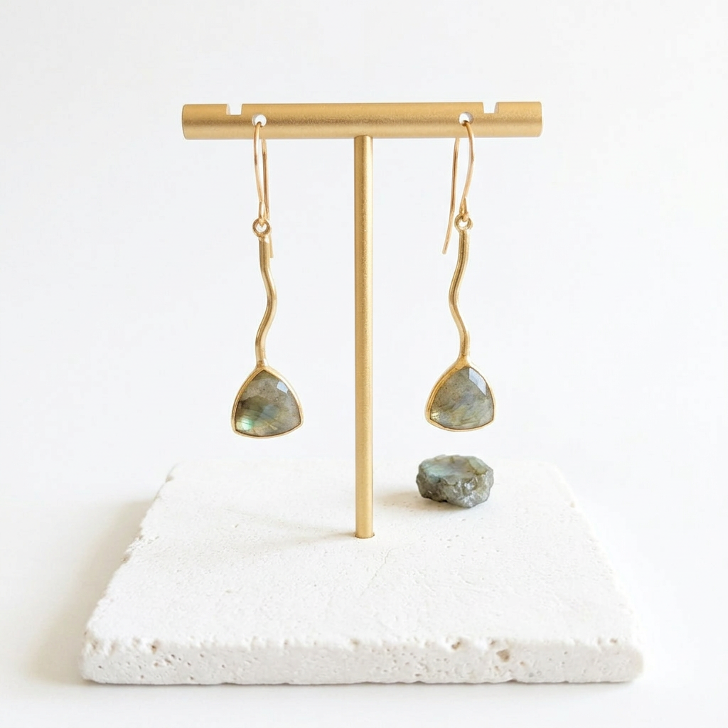 Gold zigzag drop earrings with genuine labradorite, hanging on a gold stand