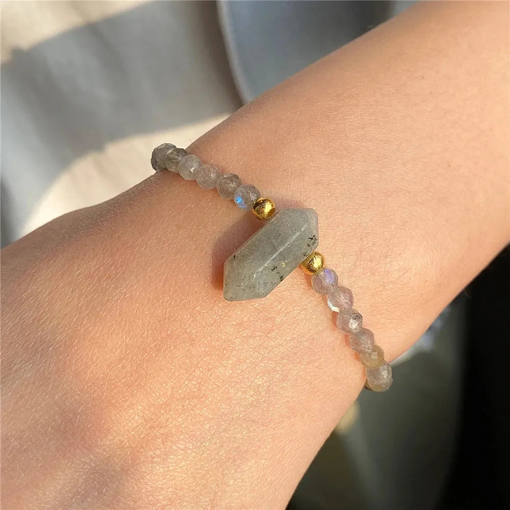 Bracelet with beads and geometric stone on wrist against a neutral background