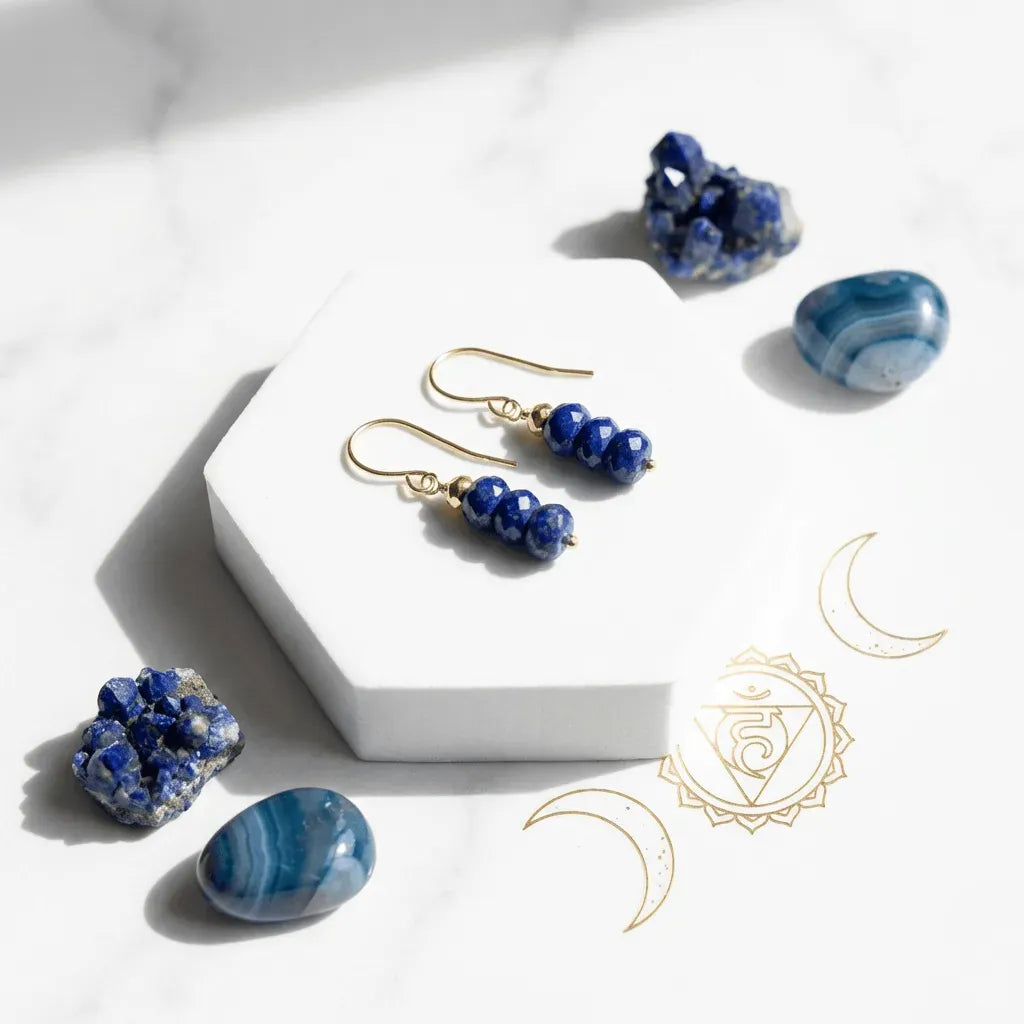 Gold earrings with blue beads on a white surface with blue stones.