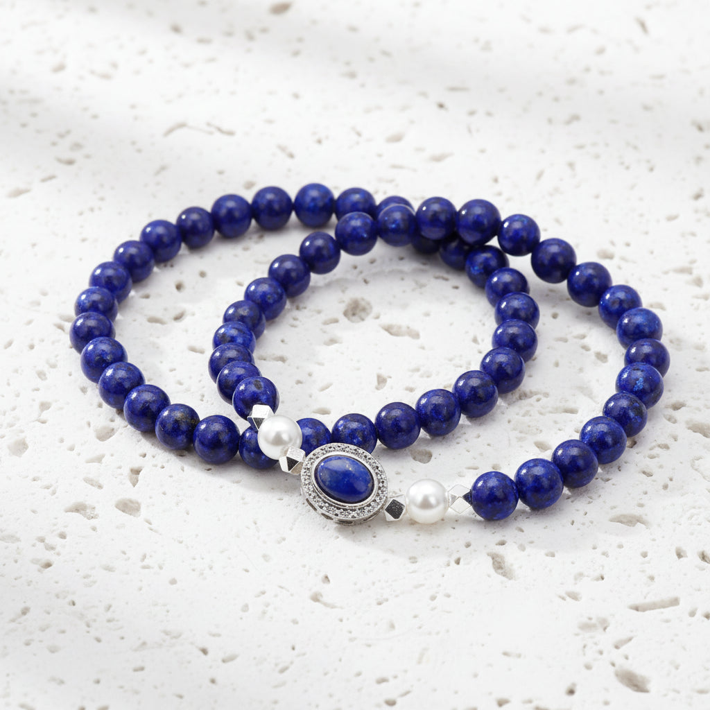 Blue beaded necklace with a white pearl and silver clasp on a white background