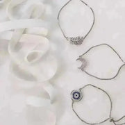 Three silver necklaces with unique pendants on a white fabric background