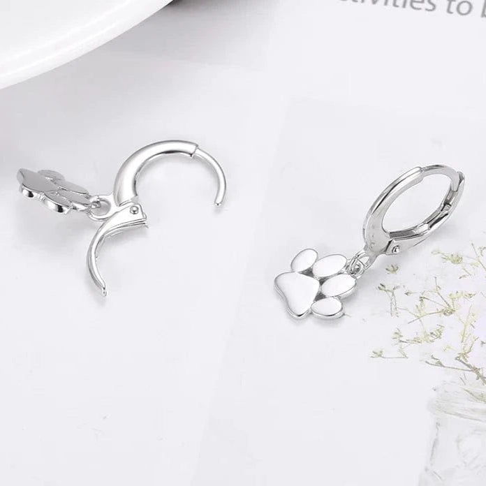 Silver hoop earrings with heart charms on a white surface