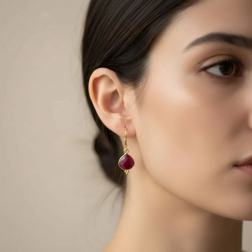 Gold earrings with red gemstones on a white background