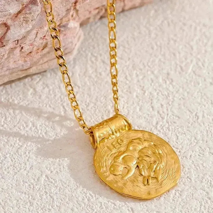 Gold necklace with a lion pendant on a textured surface