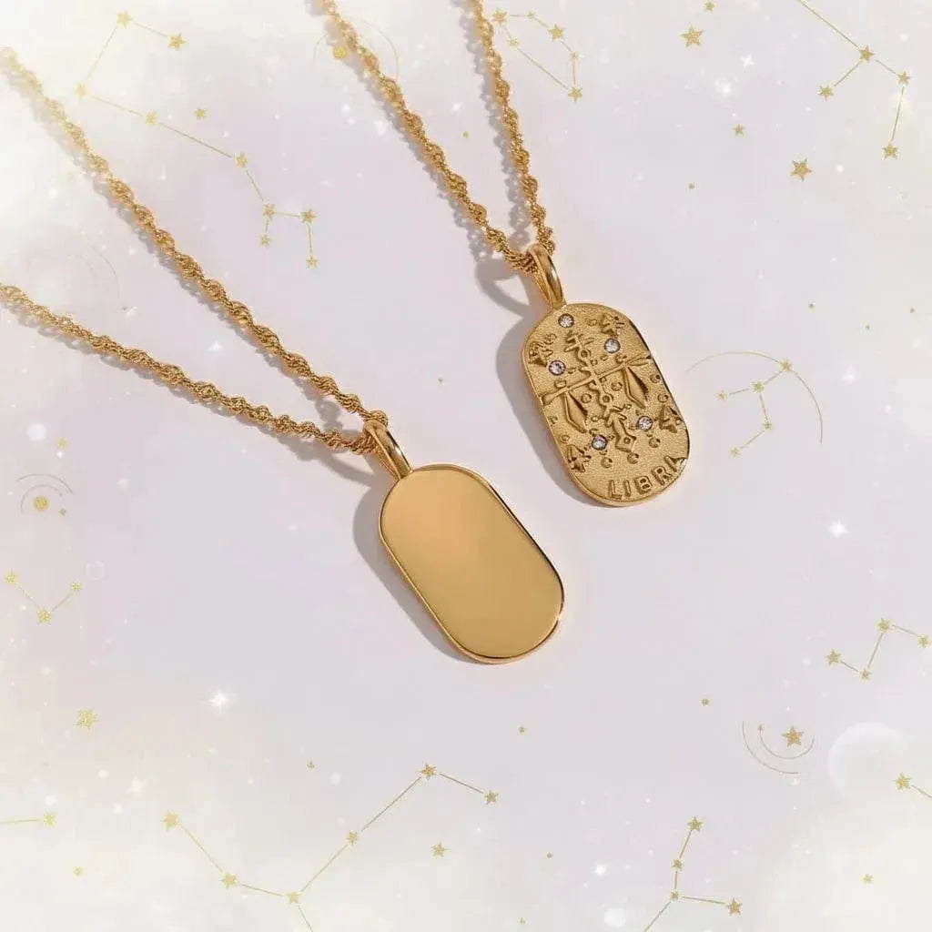 Two gold necklaces with pendants on a black stand with a white rock background