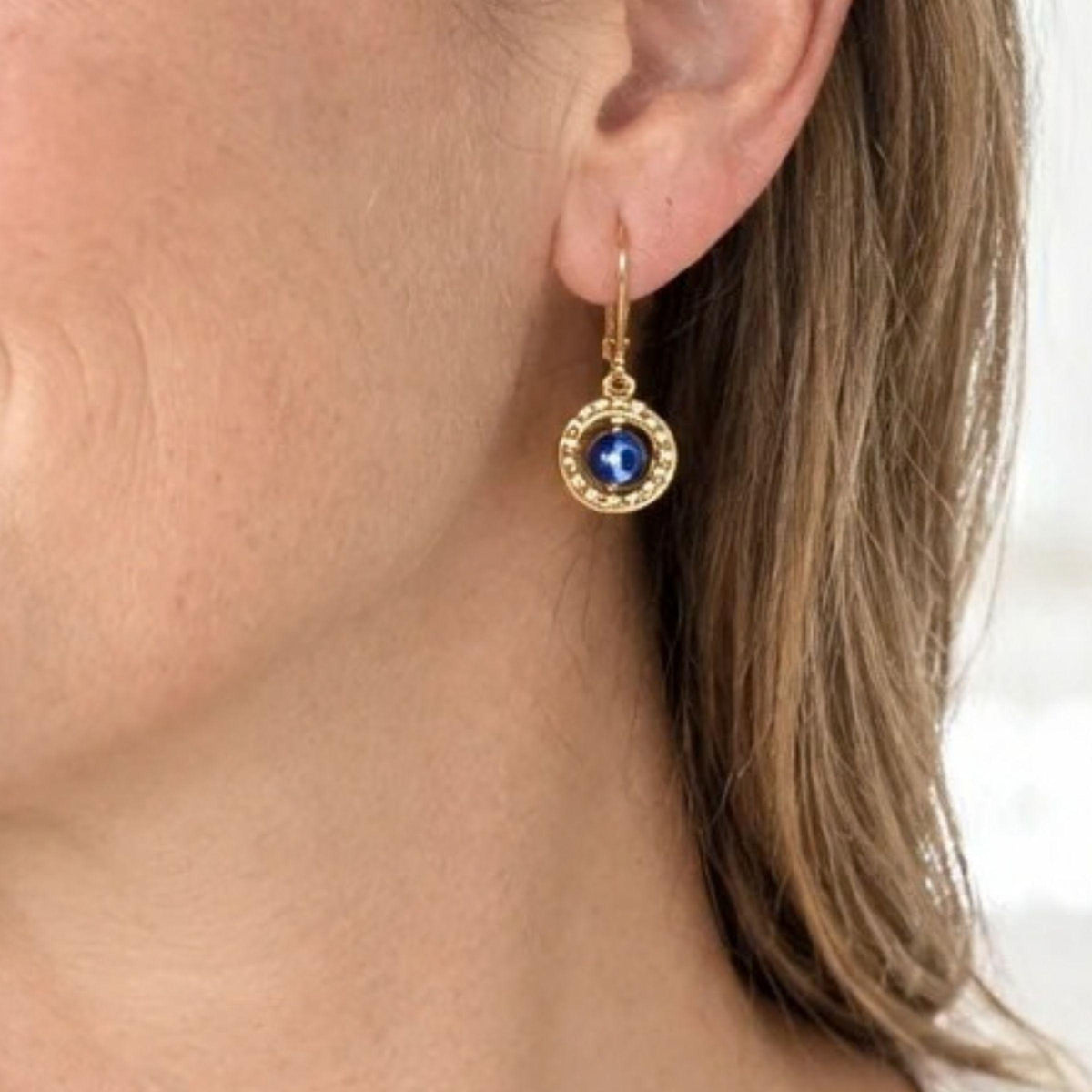 Woman wearing a floating evil eye leverback earring in gold-plated sterling silver