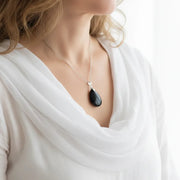 Woman wearing a black onyx teardrop necklace, shown in gold and silver, grounding gemstone jewelry