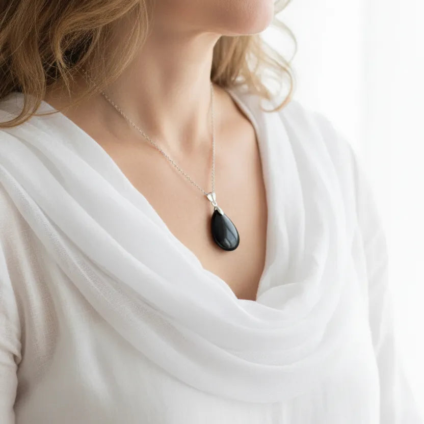 Woman wearing a black onyx teardrop necklace, shown in gold and silver, grounding gemstone jewelry