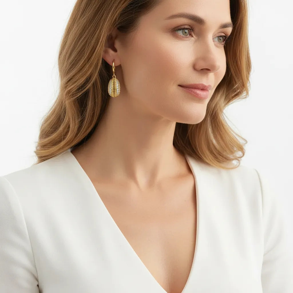 Woman wearing gold hoop earrings with cowrie shell charms